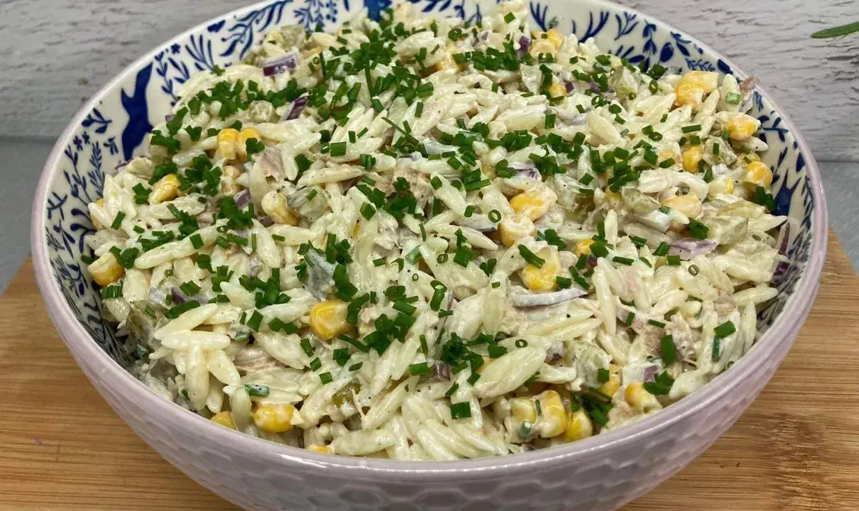 Pyszna sałatka z tuńczykiem i makaronem orzo, z kukurydzą i szczypiorkiem, w ozdobnej misce.