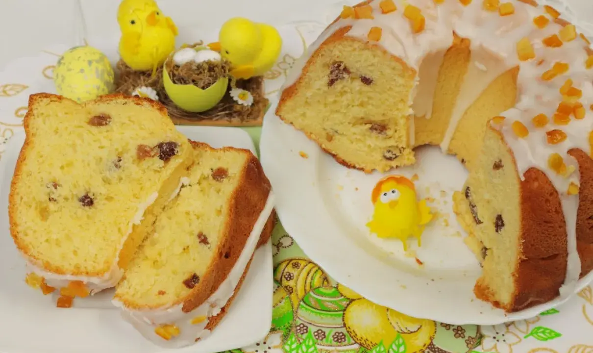 Puszysta babka drożdżowa z lukrem i kandyzowaną skórką, ozdobiona wielkanocnymi kurczaczkami.