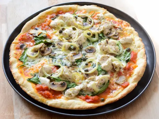 Pyszna pizza z kurczakiem, pieczarkami, szpinakiem i kaparami na cienkim cieście.