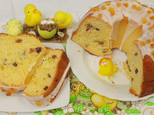 Puszysta babka drożdżowa z lukrem i kandyzowaną skórką, ozdobiona wielkanocnymi kurczaczkami.