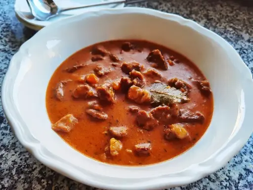 Aksamitny gulasz z łopatki w bogatym, pomidorowym sosie, z kawałkami mięsa i liściem laurowym.