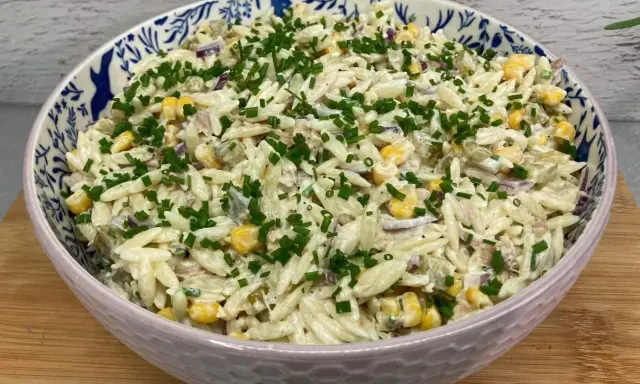 Pyszna sałatka z tuńczykiem i makaronem orzo, z kukurydzą i szczypiorkiem, w ozdobnej misce.