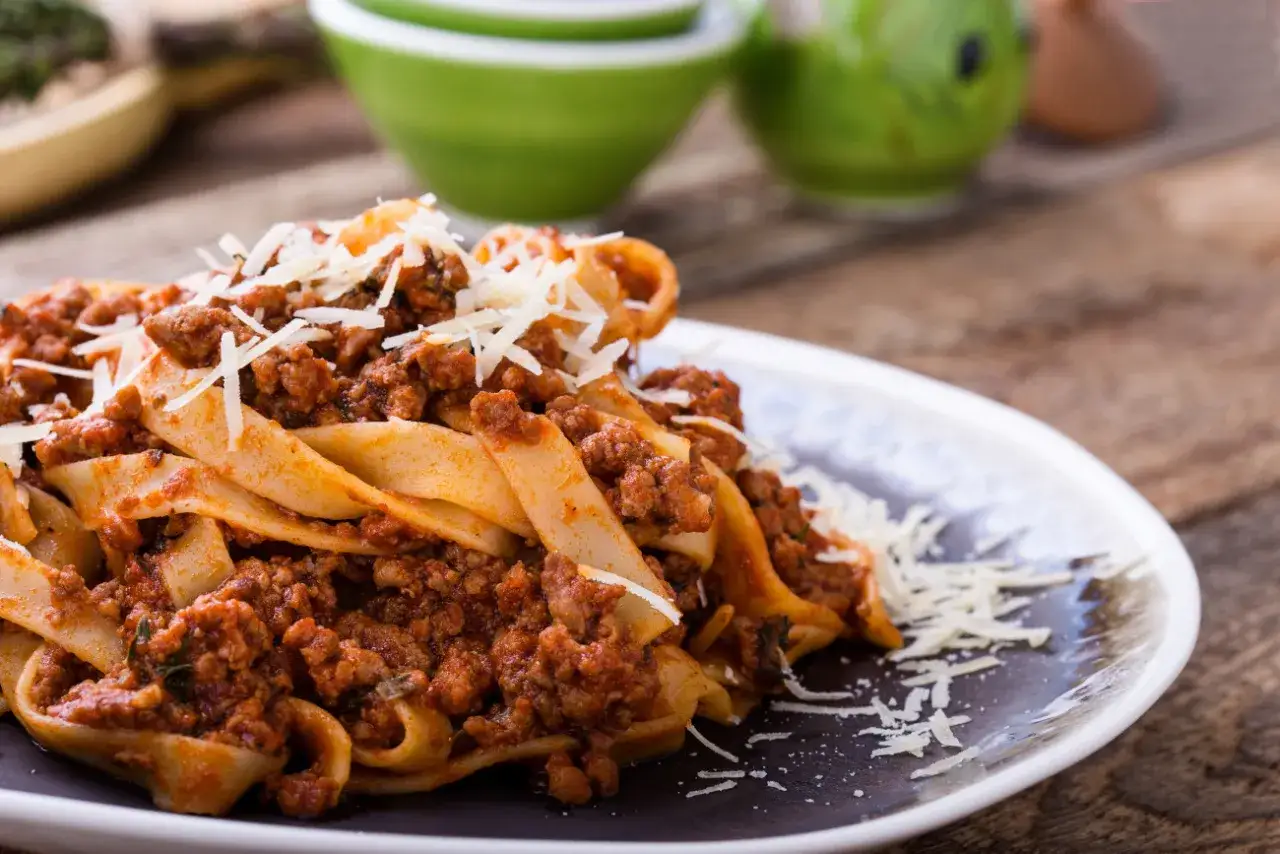 Pappardelle z bogatym sosem bolognese, posypane startym parmezanem. To pyszne mięso na spaghetti, kt&oacute;re zachwyca smakiem.
