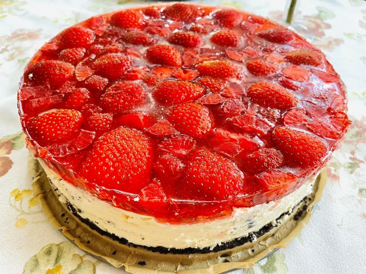 Pyszny sernik na zimno z mascarpone, obficie udekorowany świeżymi truskawkami w galaretce.