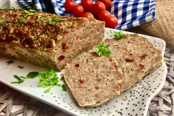 Pyszna pieczeń rzymska na kanapki, pokrojona w plastry, ozdobiona natką pietruszki. Idealna na śniadanie lub kolację.
